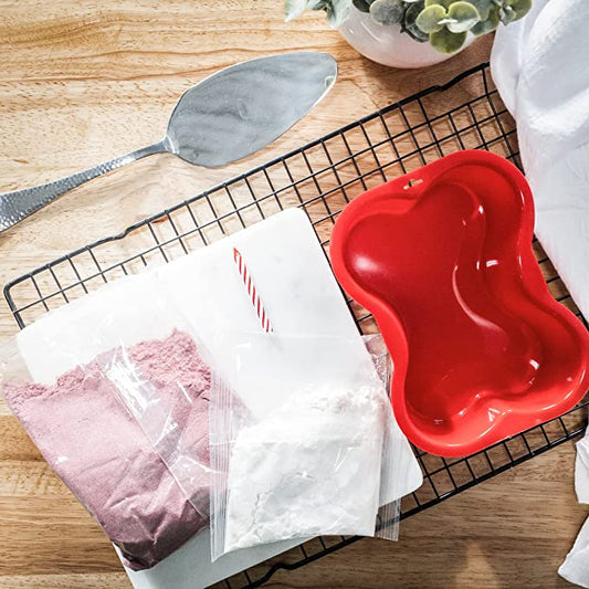 A selection of red velvet cake ingredients: flour, cocoa powder, sugar, eggs, buttermilk, and red food coloring.